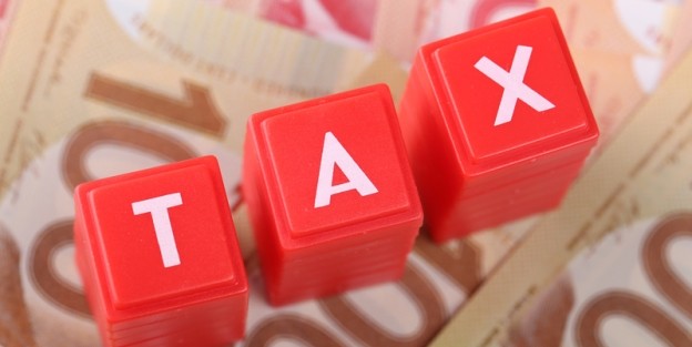 Red blocks spelling word tax on top of hundred dollar bills