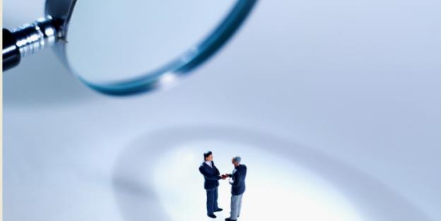 Men giving handshake under magnifying glass