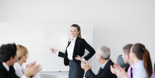 Female boss pointing at whiteboard in front of team