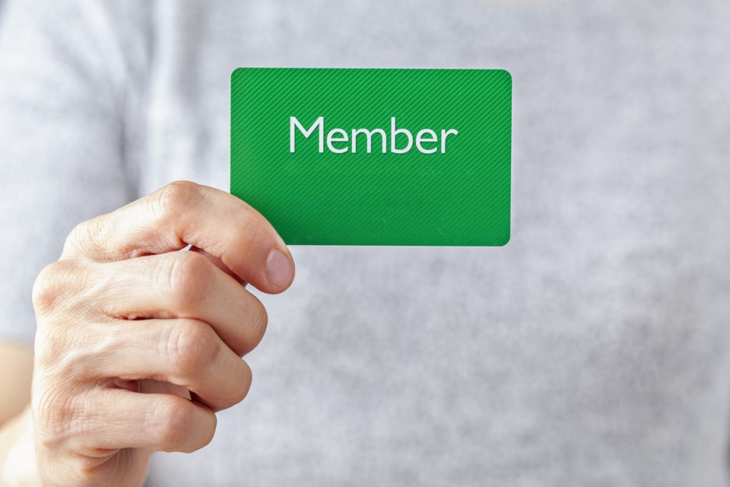 Hand holding up green member's card.