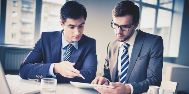 Image of two young businessmen discussing new project in office