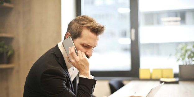 Man on phone in front of laptop
