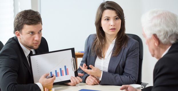 Employees updating boss and showing him chart on a monitor
