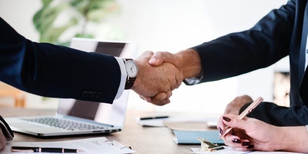 Two men shaking hands over a business table