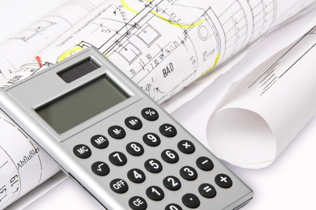 Photo of calculator and architect plans rolled up