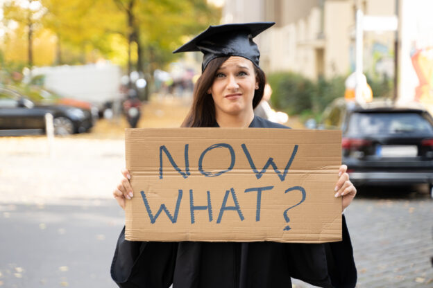 Graduate student holding up Now What sign