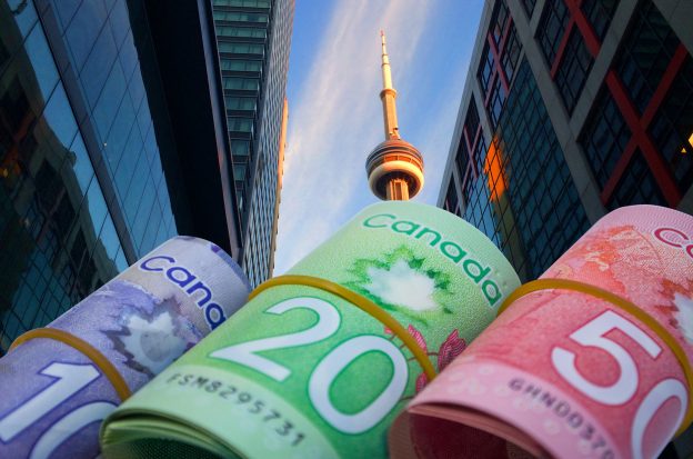 Canadian $10, $20 and $50 bills in rolls with CN Tower in background
