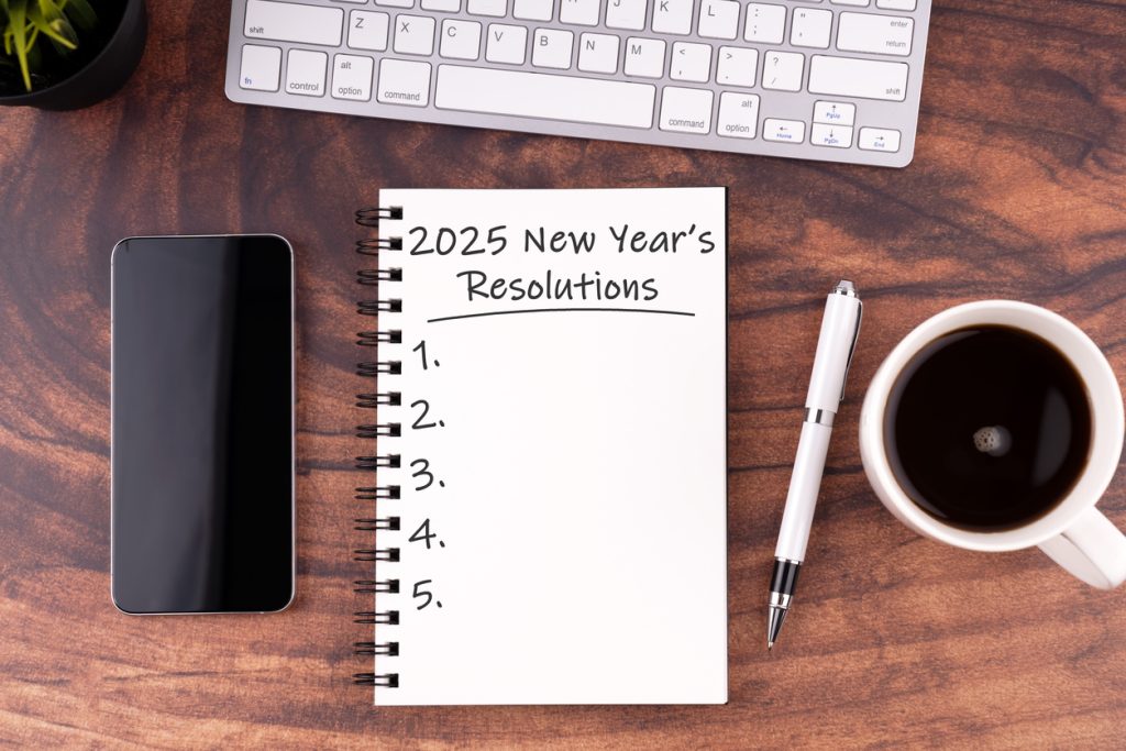 New Year's Resolutions 2025 text on note pad on wood desk