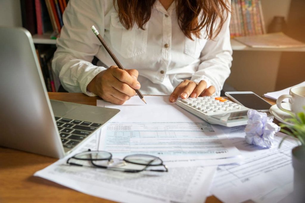 A woman working with a calculator and pencil reviewing some forms.